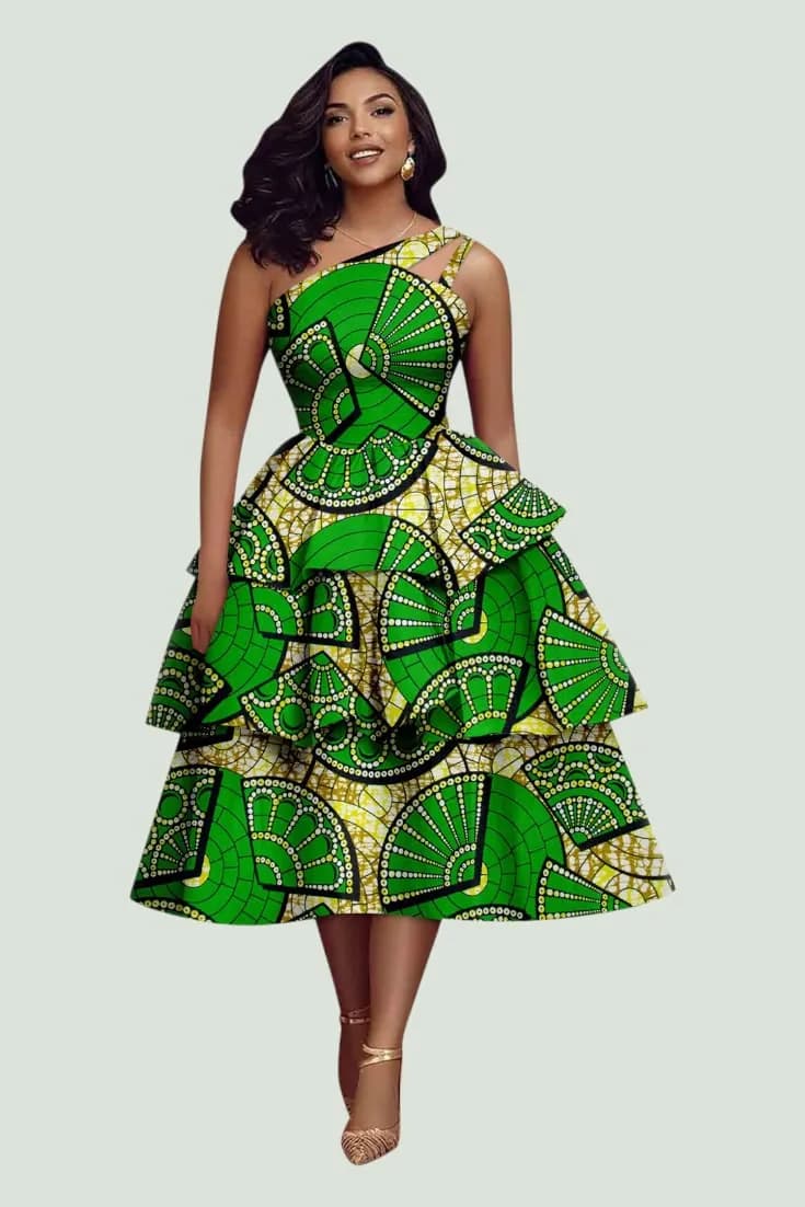 Woman in a green fan-print Ankara dress with an asymmetric neckline and tiered skirt